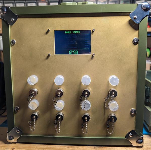 Olive vault console with a status display reading MODUL STATUS above a clock, below it two rows of four chrome dome-shaped indicator LEDs, each above a circular connector with a chained dust cap