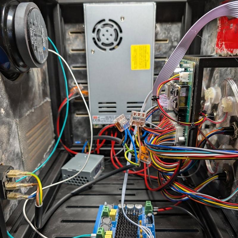 Interior of the hub showing a coaxial loudspeaker, an enclosed switch-mode power supply, a class-D amplifier board with heatsink, a green custom PCB with ribbon cable and colour-coded wiring harnesses