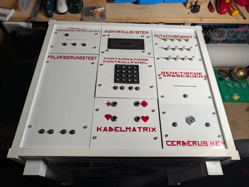 The white console photographed from the front in a workshop, showing the Umbrella logo, the twelve unlit indicator LEDs in their metal strip, two translucent tubes at the corners and the switch panels on top