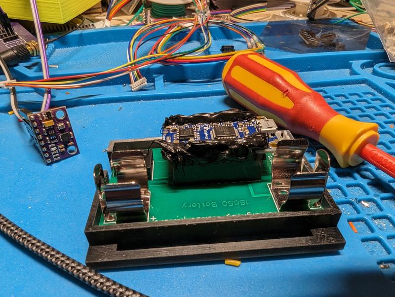 Close-up of the carrier board in its printed frame, with two pairs of metal 18650 clips and the audio module sealed under black potting compound